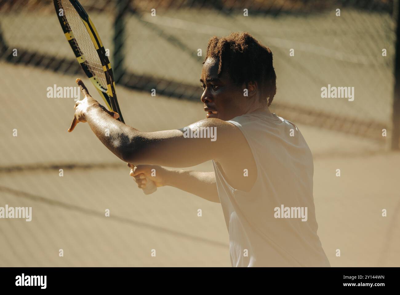 Uomo afro-americano che dimostra un intenso colpo di fronte durante una partita di tennis su una superficie di campo duro. Foto Stock