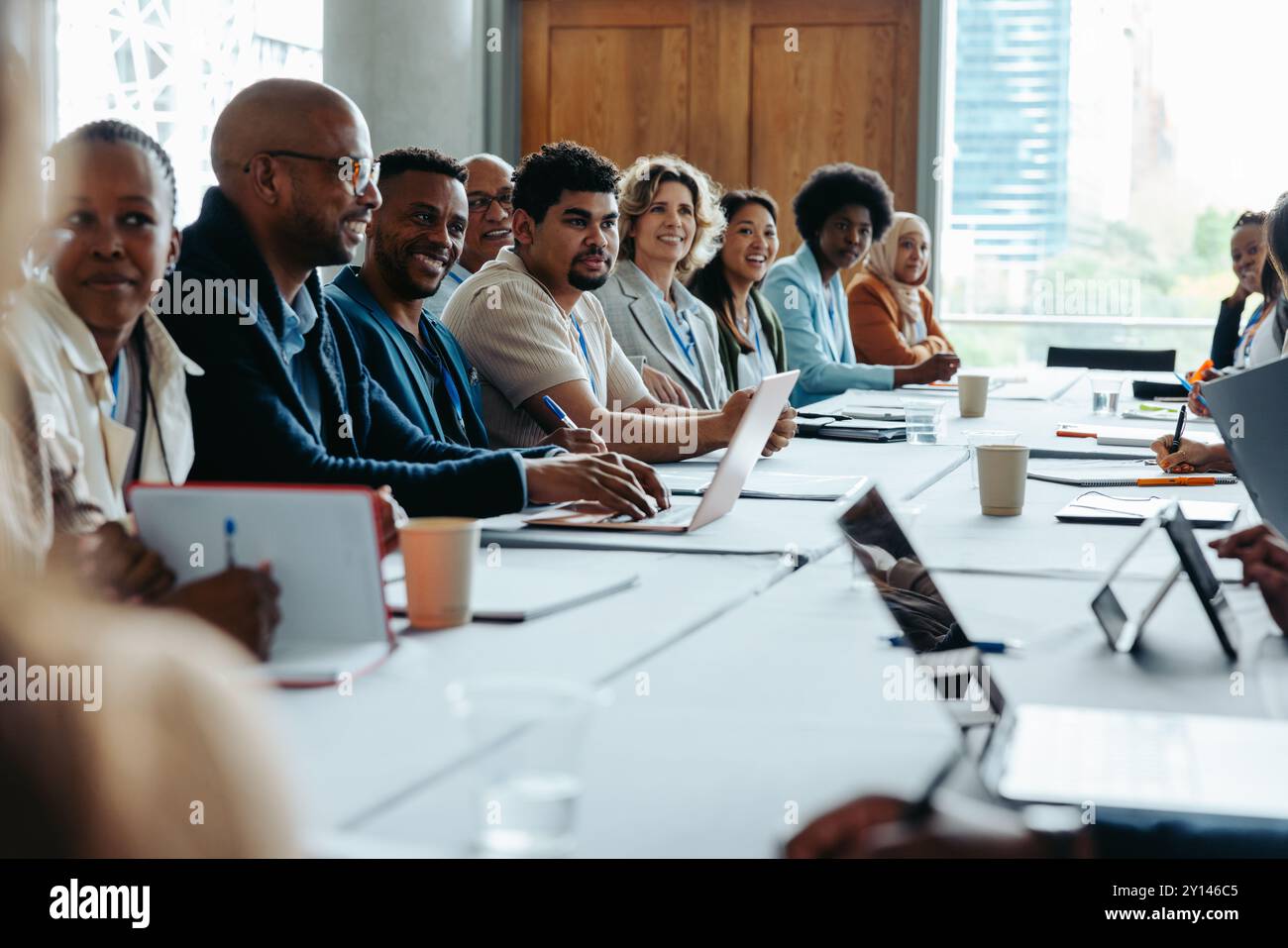 Un team diversificato partecipa a una vivace conferenza aziendale, condividendo idee e strategie in un moderno ambiente aziendale. Foto Stock