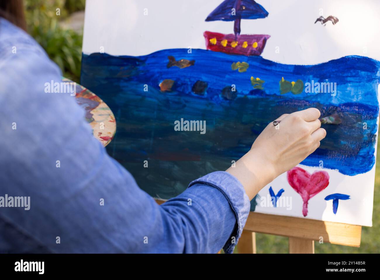 Creare opere d'arte all'aperto, dipingere una barca colorata su tela Foto Stock