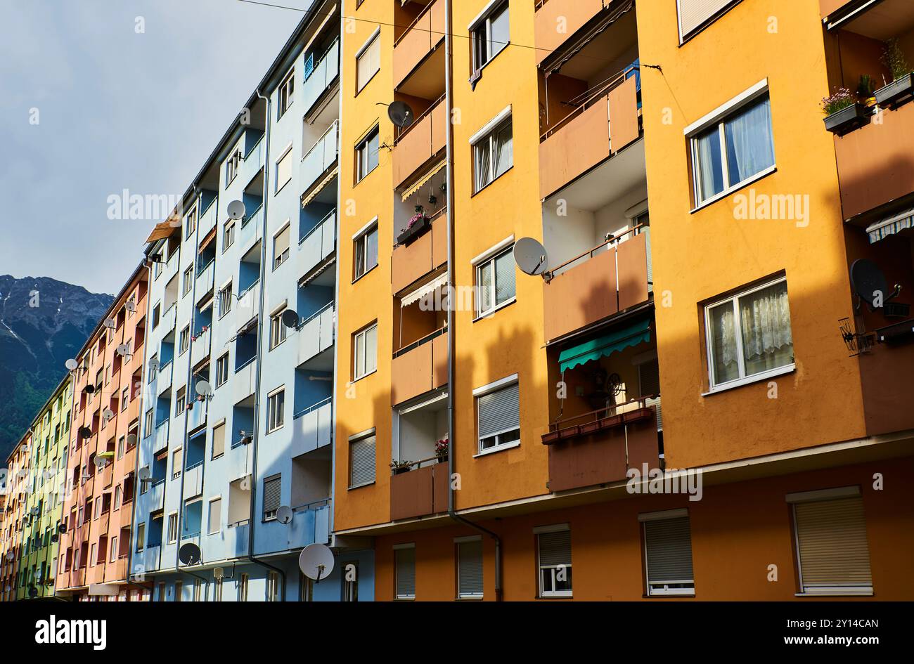 Stile di vita moderno con vicini che vivono insieme in un edificio colorato pieno di appartamenti con parabole satellitari a Innsbruck, Austria. Facciata affollata Foto Stock