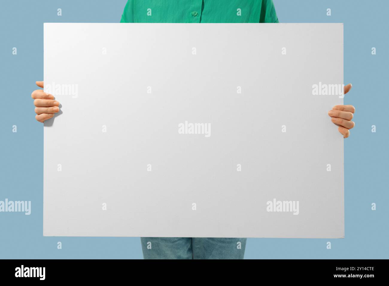 Persona irriconoscibile che tiene in mano una tela bianca con spazio vuoto per il testo nelle mani Foto Stock