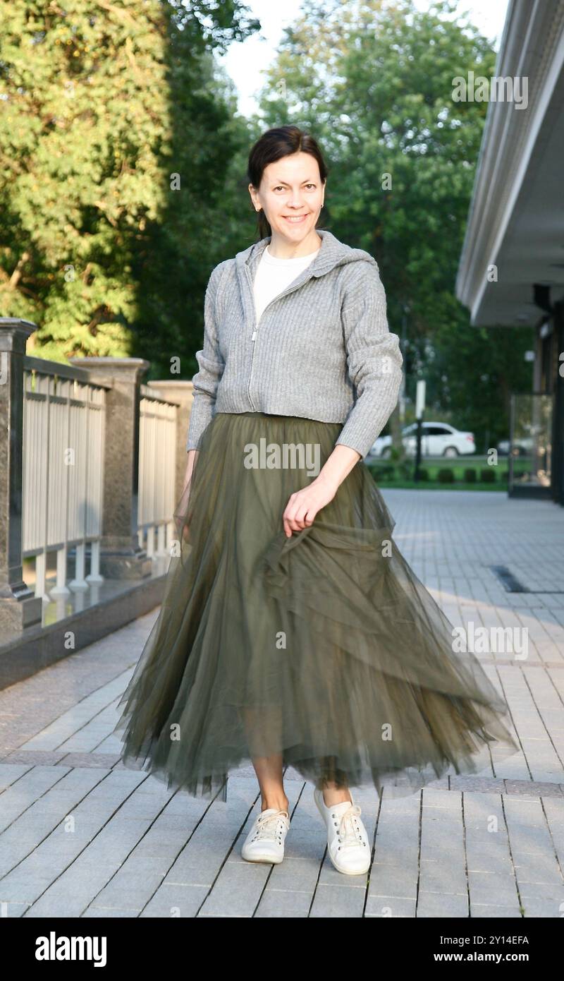 Donna di mezza età in elegante gonna verde in tulle sorridente e volteggiante Foto Stock