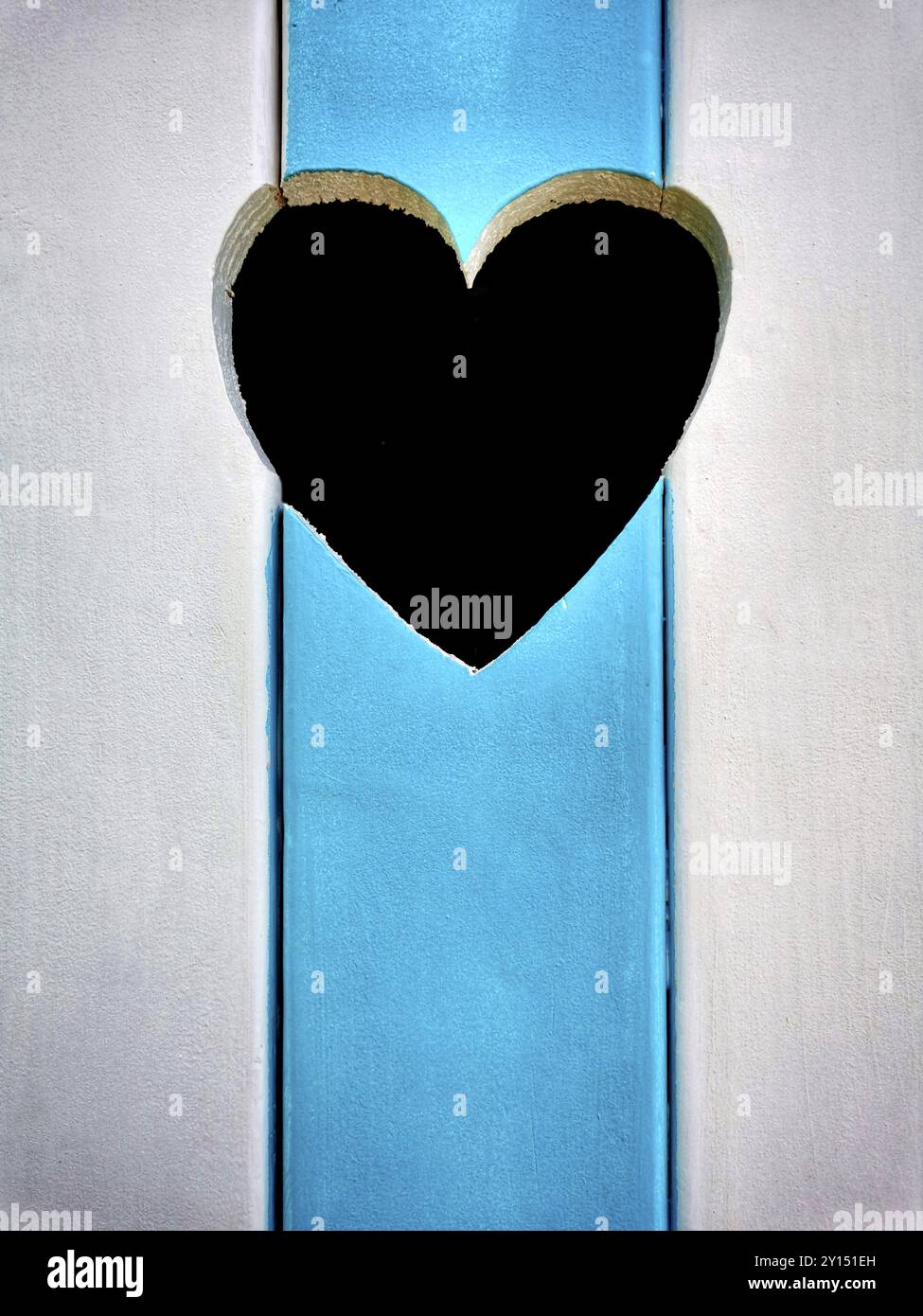 L'incantevole capanna sulla spiaggia presenta una fessura a forma di cuore e vivaci strisce blu e bianche sullo sfondo del cielo limpido Foto Stock