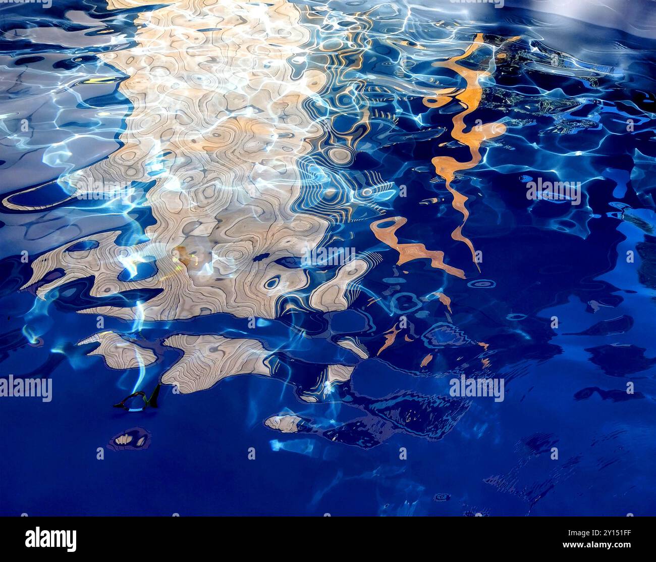 Riflessi accattivanti sulla tranquilla superficie dell'acqua catturati durante una giornata luminosa a bordo piscina con morbide increspature e texture Foto Stock