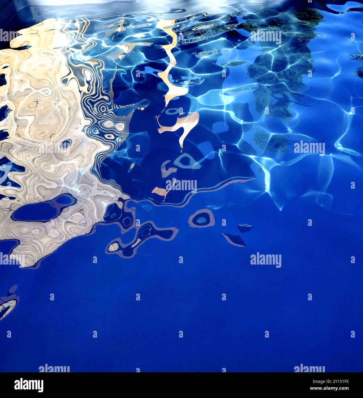 Riflessi accattivanti sulla tranquilla superficie dell'acqua catturati durante una giornata luminosa a bordo piscina con morbide increspature e texture Foto Stock