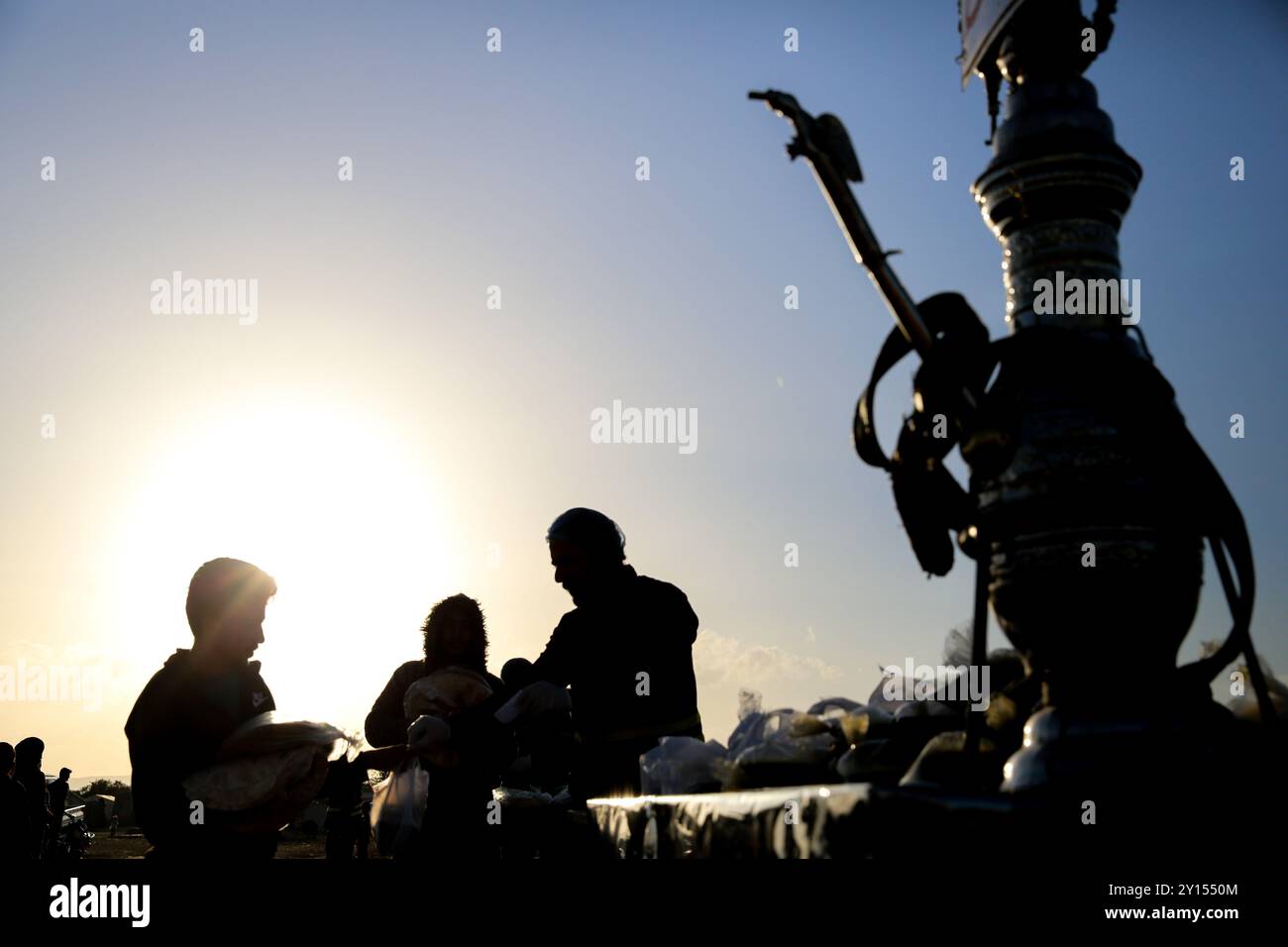 Idlib, Siria. 19 aprile 2022. Varie organizzazioni distribuiscono pasti iftar e succhi di tamarindo e bevande liquirizie ai residenti dei campi di sfollamento vicino a Sarmada, nel governatorato di Idlib, durante il Ramadan. Le difficoltà incontrate dagli sfollati residenti nei campi della roccaforte dell'opposizione di Idlib hanno esacerbato la crisi fiscale in Turchia e la caduta della lira turca, nonché la crisi Ucraina in corso e le conseguenti carenze alimentari Foto Stock