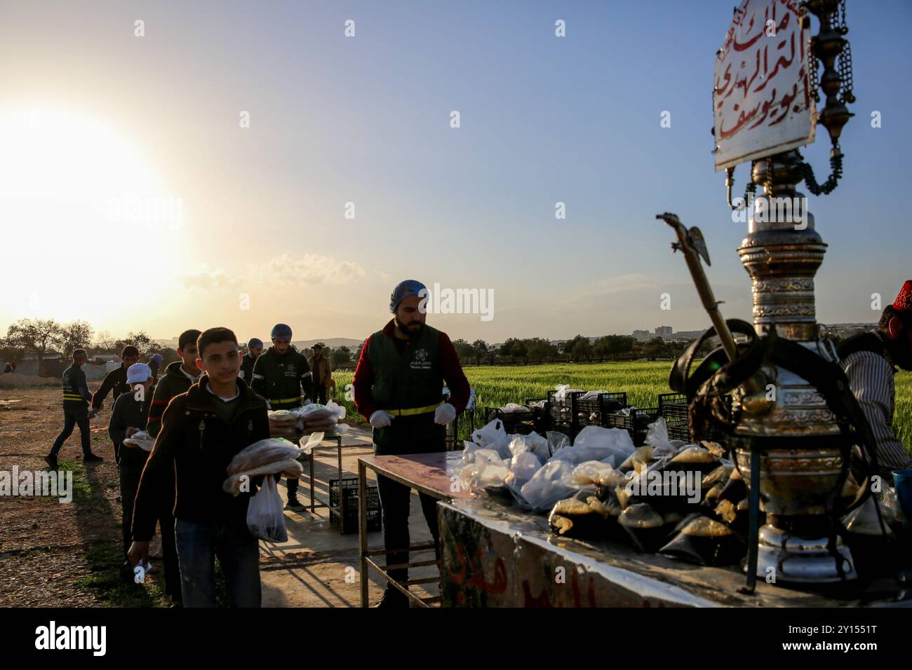 Idlib, Siria. 19 aprile 2022. Varie organizzazioni distribuiscono pasti iftar e succhi di tamarindo e bevande liquirizie ai residenti dei campi di sfollamento vicino a Sarmada, nel governatorato di Idlib, durante il Ramadan. Le difficoltà incontrate dagli sfollati residenti nei campi della roccaforte dell'opposizione di Idlib hanno esacerbato la crisi fiscale in Turchia e la caduta della lira turca, nonché la crisi Ucraina in corso e le conseguenti carenze alimentari Foto Stock