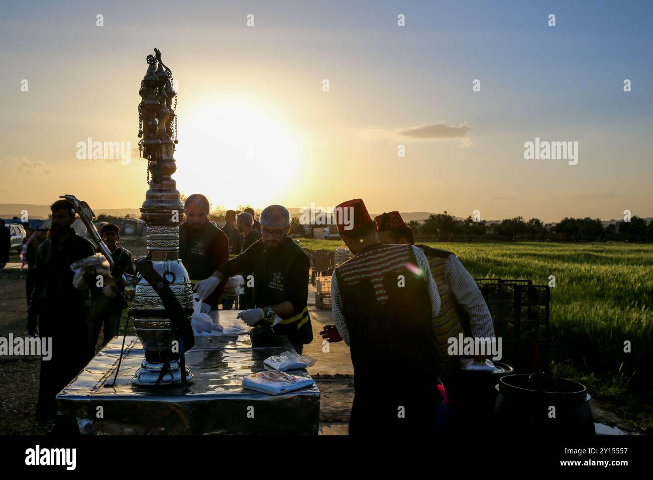 Idlib, Siria. 19 aprile 2022. Varie organizzazioni distribuiscono pasti iftar e succhi di tamarindo e bevande liquirizie ai residenti dei campi di sfollamento vicino a Sarmada, nel governatorato di Idlib, durante il Ramadan. Le difficoltà incontrate dagli sfollati residenti nei campi della roccaforte dell'opposizione di Idlib hanno esacerbato la crisi fiscale in Turchia e la caduta della lira turca, nonché la crisi Ucraina in corso e le conseguenti carenze alimentari Foto Stock