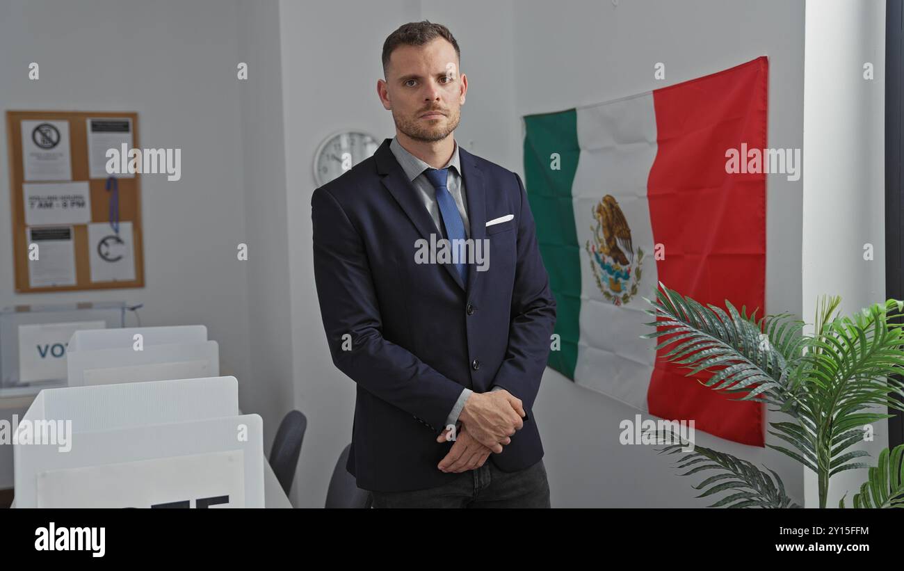 Un uomo serio con una tuta si trova assertivamente al chiuso con una bandiera messicana sullo sfondo, a simboleggiare l'autorità e il governo. Foto Stock