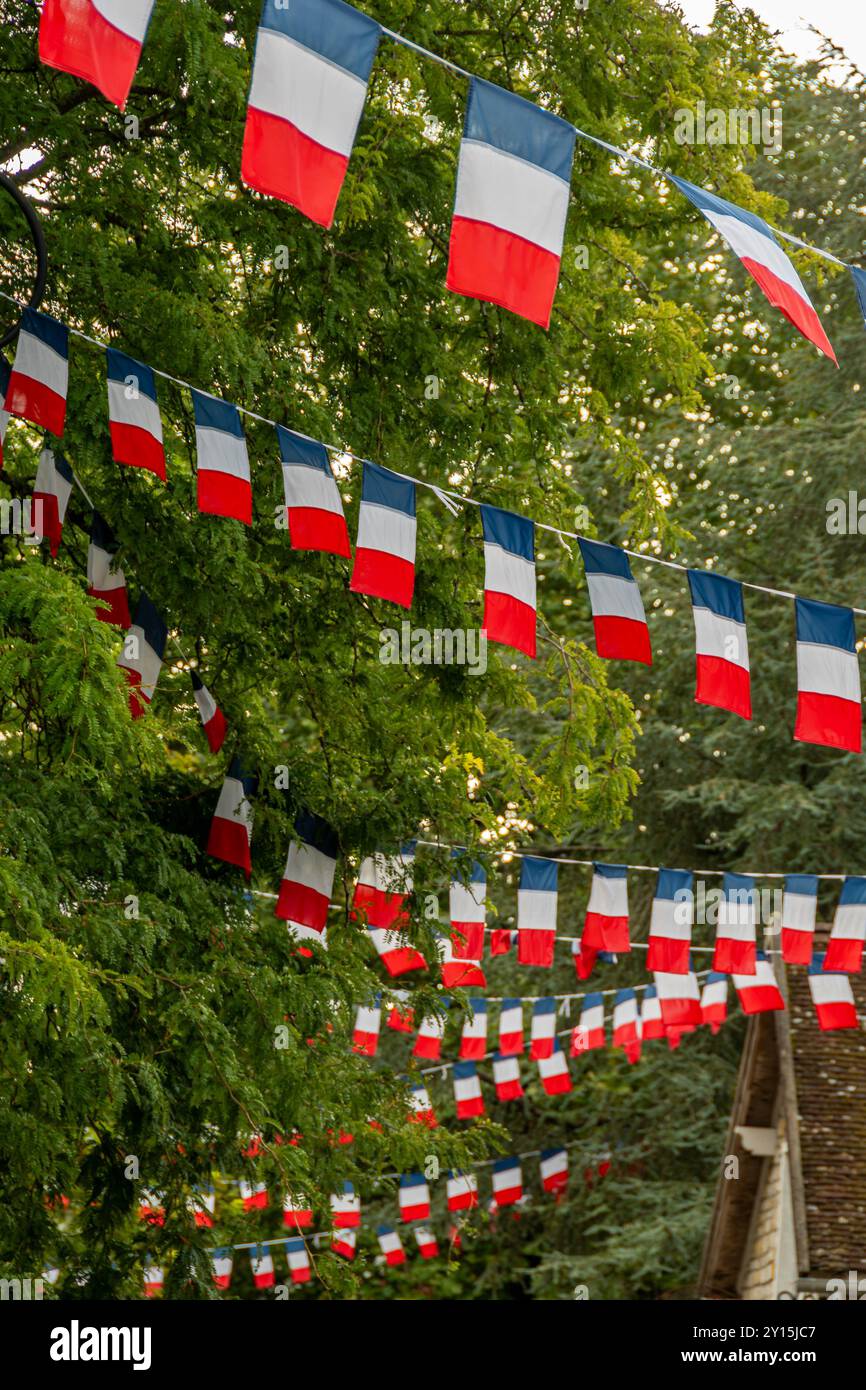 Disposizione di ghirlande di bandiera tricolore francese che decorano una strada di un villaggio in Francia. Concetti del giorno della Bastiglia e festa francese o evento patriottico Foto Stock
