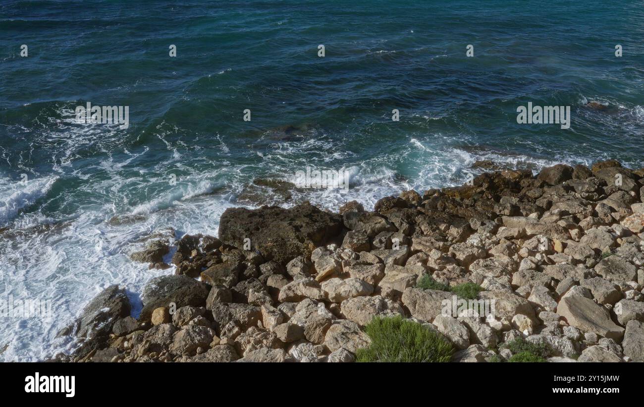 Onde che si infrangono contro la costa rocciosa di gallipoli, una città costiera in puglia, salento, italia, che mostra il vivace mare blu e la costa frastagliata su un'isola Foto Stock