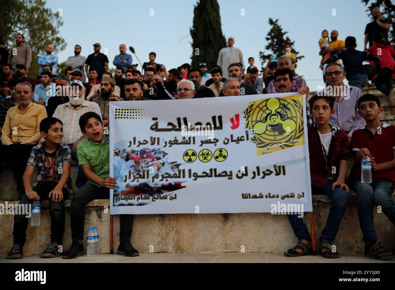 Agosto 2013. Una veglia si tiene a Idlib per commemorare il nono anniversario di un presunto attacco chimico da parte delle forze governative siriane a Ghouta orientale. I manifestanti hanno tenuto striscioni che ritenevano il governo di Bashar al-Assad responsabile dell'attacco e chiedevano giustizia a nome delle vittime. Si ritiene che più di 1.400 civili siano morti in un attacco con armi chimiche nella parte orientale di Ghouta e nelle aree di Muadamiyat al-Sham di Damasco il 21 agosto 2013. Un certo numero di militanti armati del gruppo di opposizione Hay'at Tahrir al-Sham hanno partecipato alla veglia Foto Stock