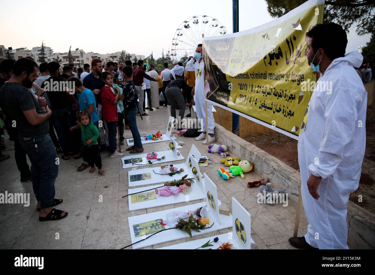 Agosto 2013. Una veglia si tiene a Idlib per commemorare il nono anniversario di un presunto attacco chimico da parte delle forze governative siriane a Ghouta orientale. I manifestanti hanno tenuto striscioni che ritenevano il governo di Bashar al-Assad responsabile dell'attacco e chiedevano giustizia a nome delle vittime. Si ritiene che più di 1.400 civili siano morti in un attacco con armi chimiche nella parte orientale di Ghouta e nelle aree di Muadamiyat al-Sham di Damasco il 21 agosto 2013. Un certo numero di militanti armati del gruppo di opposizione Hay'at Tahrir al-Sham hanno partecipato alla veglia Foto Stock