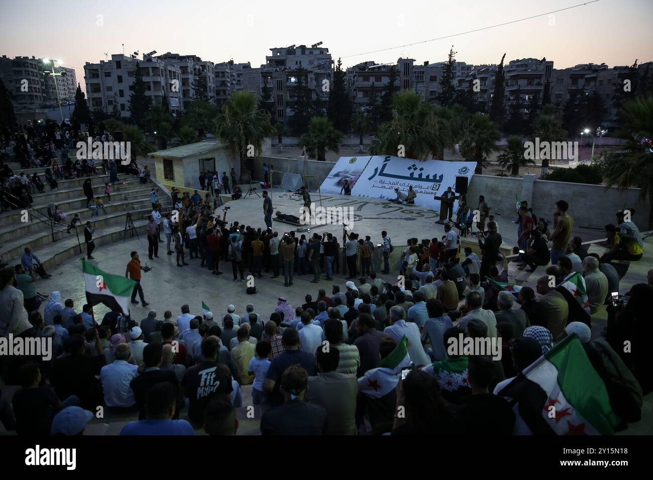 Agosto 2013. Una veglia si tiene a Idlib per commemorare il nono anniversario di un presunto attacco chimico da parte delle forze governative siriane a Ghouta orientale. I manifestanti hanno tenuto striscioni che ritenevano il governo di Bashar al-Assad responsabile dell'attacco e chiedevano giustizia a nome delle vittime. Si ritiene che più di 1.400 civili siano morti in un attacco con armi chimiche nella parte orientale di Ghouta e nelle aree di Muadamiyat al-Sham di Damasco il 21 agosto 2013. Un certo numero di militanti armati del gruppo di opposizione Hay'at Tahrir al-Sham hanno partecipato alla veglia Foto Stock