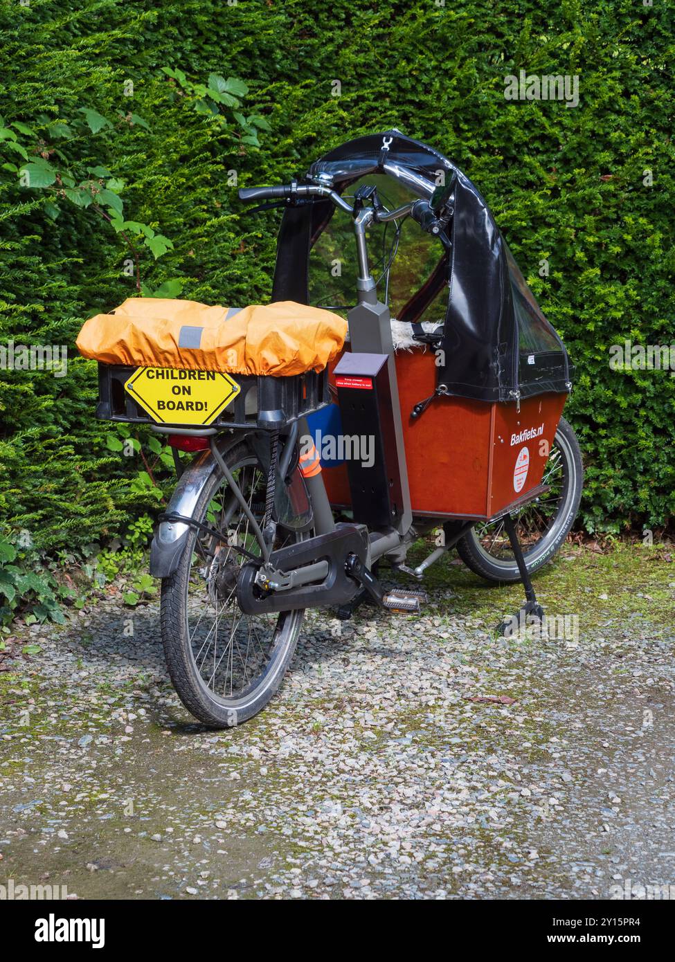 Bici da carico elettrica Bakfiets di fabbricazione olandese configurata per il trasporto di bambini nel supporto anteriore coperto Foto Stock