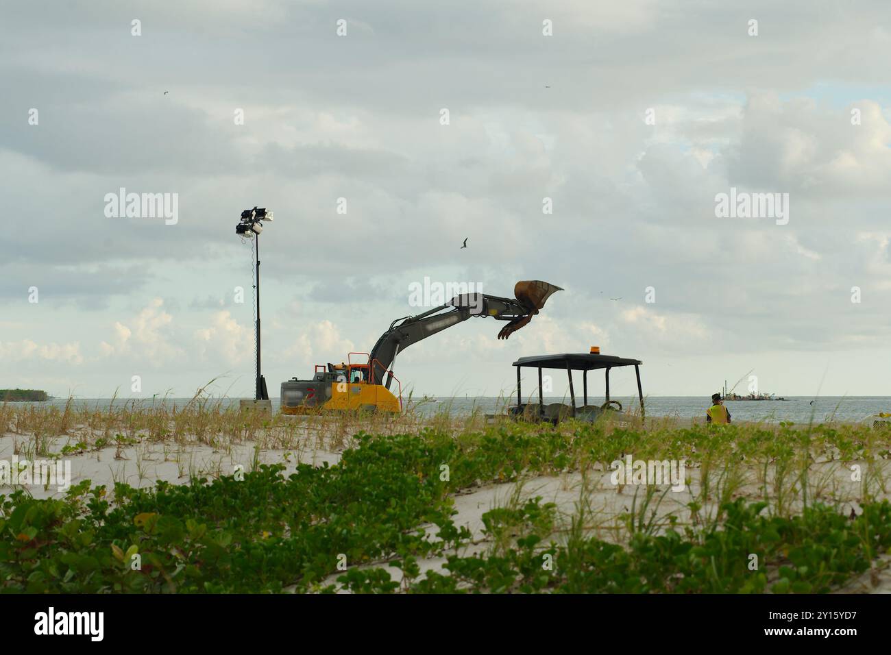 St. Pete Beach, Florida, verso il Golfo del Messico come macchine pesanti lavorano sul nutrimento delle spiagge . Vista su sabbia e avena marina. In un giorno nuvoloso in ritardo nel dopo Foto Stock