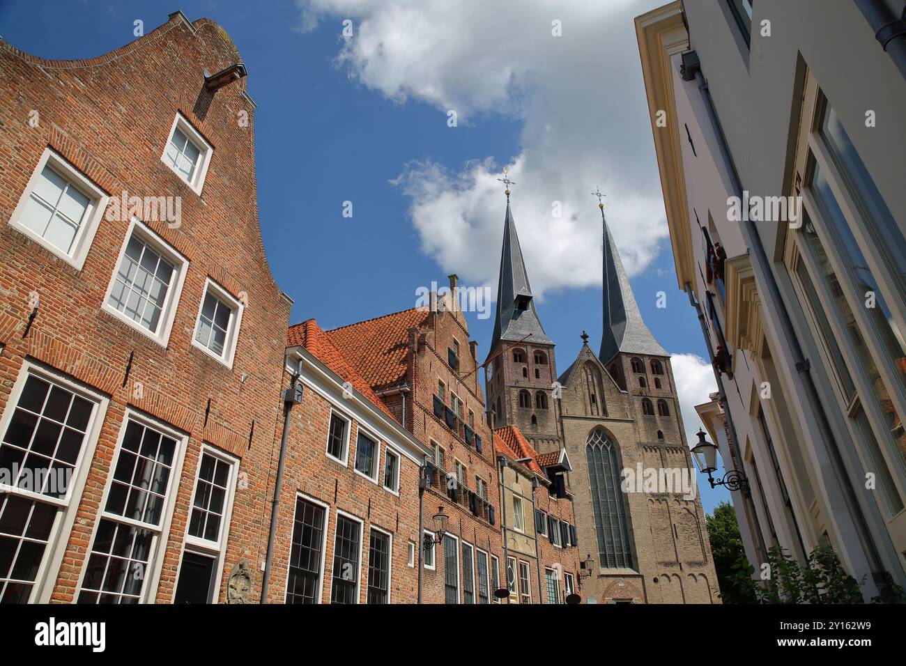 Storiche case medievali, situate nel quartiere Bergkwartier di Deventer, Overijssel, Paesi Bassi, con le due torri della chiesa di San Nicola Foto Stock