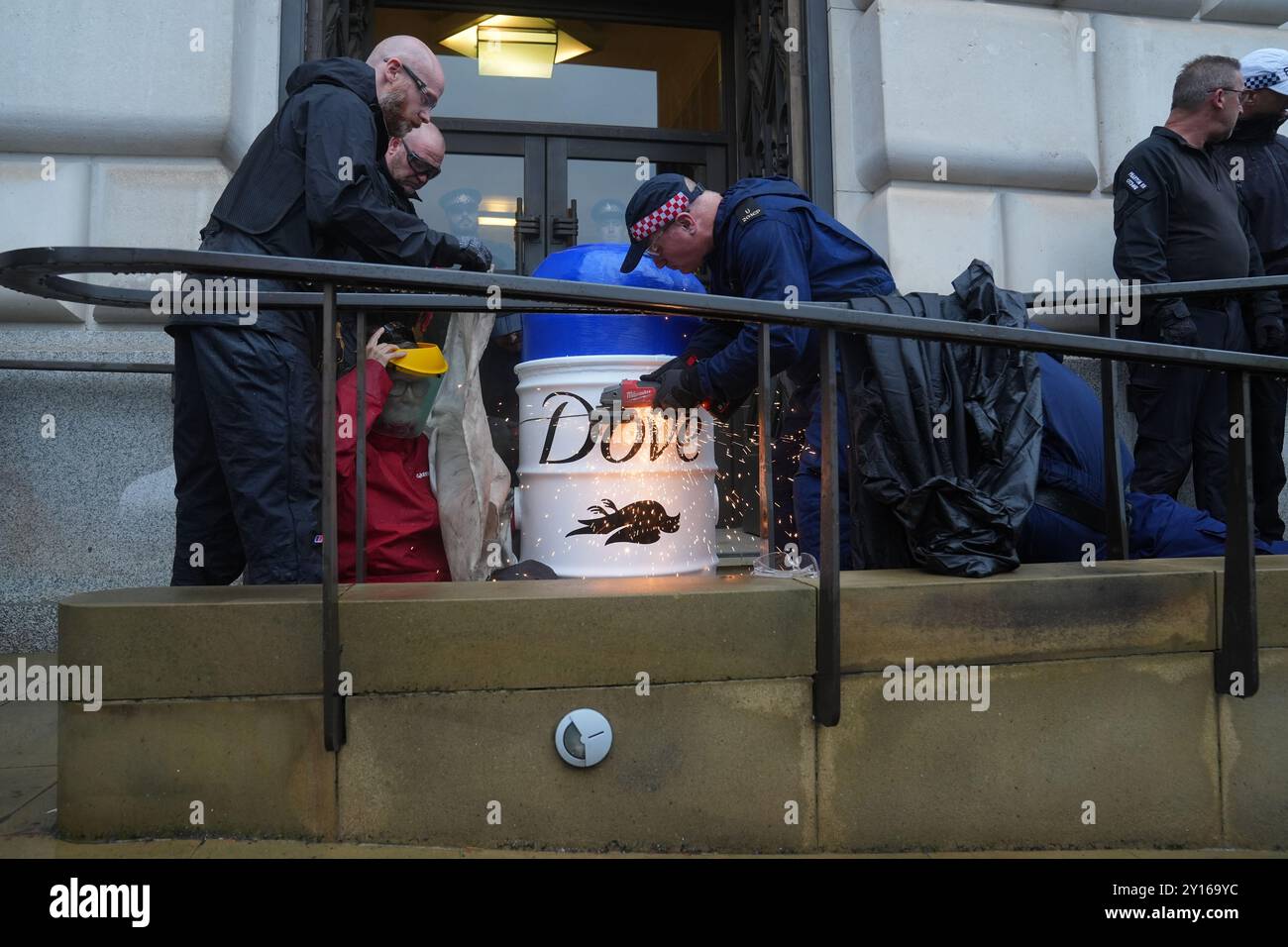 La polizia rimuove gli attivisti fuori dalla sede centrale di Unilever nel centro di Londra poiché Greenpeace UK ha bloccato l'accesso all'edificio sostenendo che l'azienda di beni di consumo sta "distruggendo il pianeta e danneggiando le comunità" attraverso la plastica monouso. I membri del gruppo ambientalista si sono bloccati su barricate realizzate con prodotti giganti dove, uno dei più grandi marchi di Unilever, con il logo di ogni prodotto cambiato in Dead dove. Data foto: Giovedì 5 settembre 2024. Foto Stock