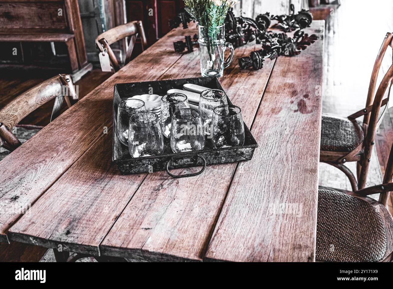 Primo piano di tazze di vetro in vassoio di latta su un tavolo di fattoria in stile "Distressed" con lo sfondo di porte in legno al Farmhouse Style Store Foto Stock