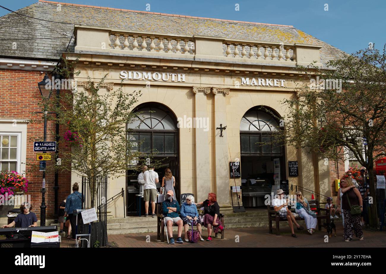 Mercato al coperto di Sidmouth con turisti, pubblico seduto all'esterno nella piazza del mercato, Sidmouth, Devon, Regno Unito Foto Stock