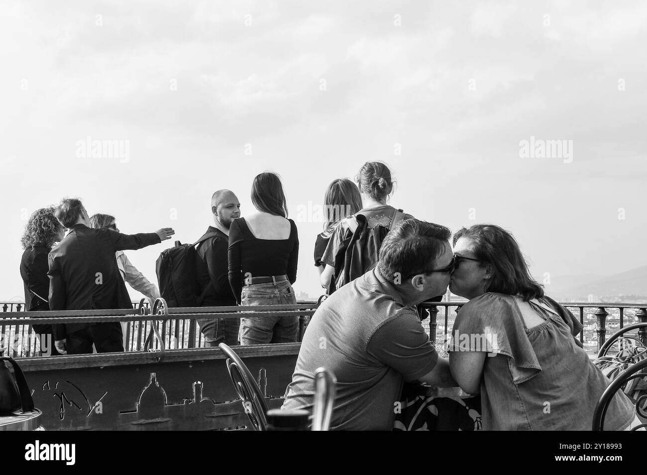 B&W Una coppia amorevole si bacierà in un caffè con terrazza con turisti che ammirano la vista del centro storico di Firenze sullo sfondo, Toscana, Italia Foto Stock