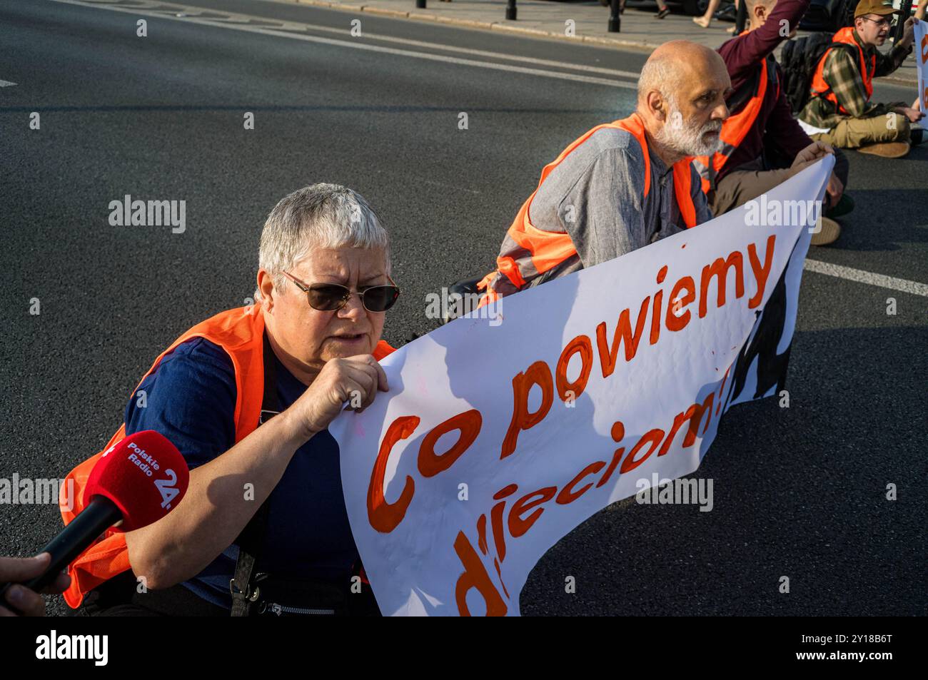 Un attivista per il clima è intervistato dalla radio polacca mentre blocca la strada. La mattina del 5 settembre, un gruppo di attivisti di Ostatnie Pokolenie (l'ultima generazione) blocca la strada sotto la chiesa di Sant'Alessandro sulla piazza delle tre croci di Varsavia. L'azione è una delle tante volte a promuovere opzioni di trasporto pubblico più economiche e più ampie. Il gruppo chiede che il governo sposti il 100% del denaro stanziato per le nuove autostrade verso il trasporto pubblico regionale e introduca un biglietto a basso costo da 50 PLN per il trasporto pubblico in tutta la Polonia. La serie di blocchi stradali ha luogo Foto Stock