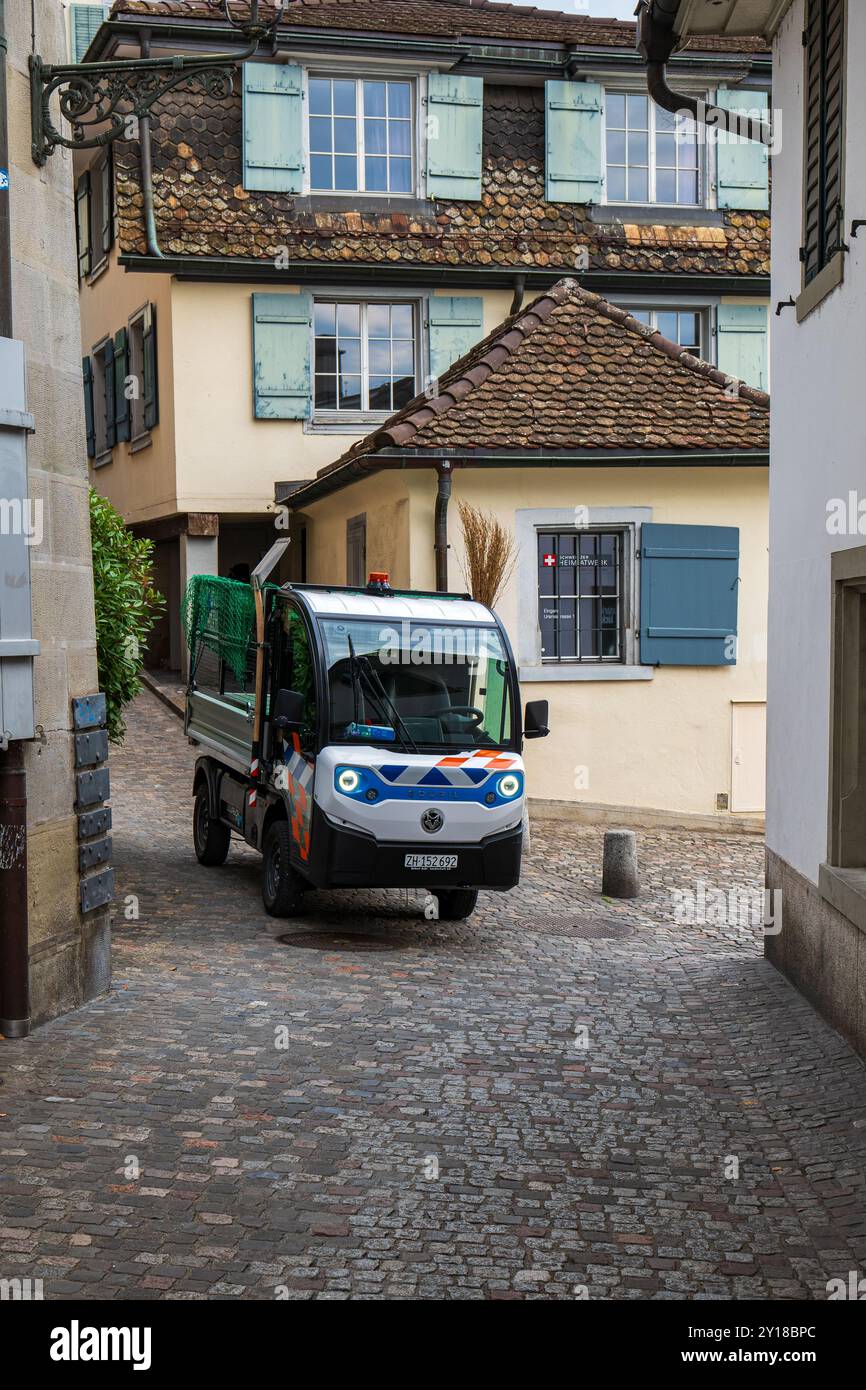 03-09-2024 Zurigo, Svizzera. Piccolo minibus elettrico su una strada stretta della città vecchia. Concetto di raccolta rifiuti, soleggiato giorno d'estate, n Foto Stock