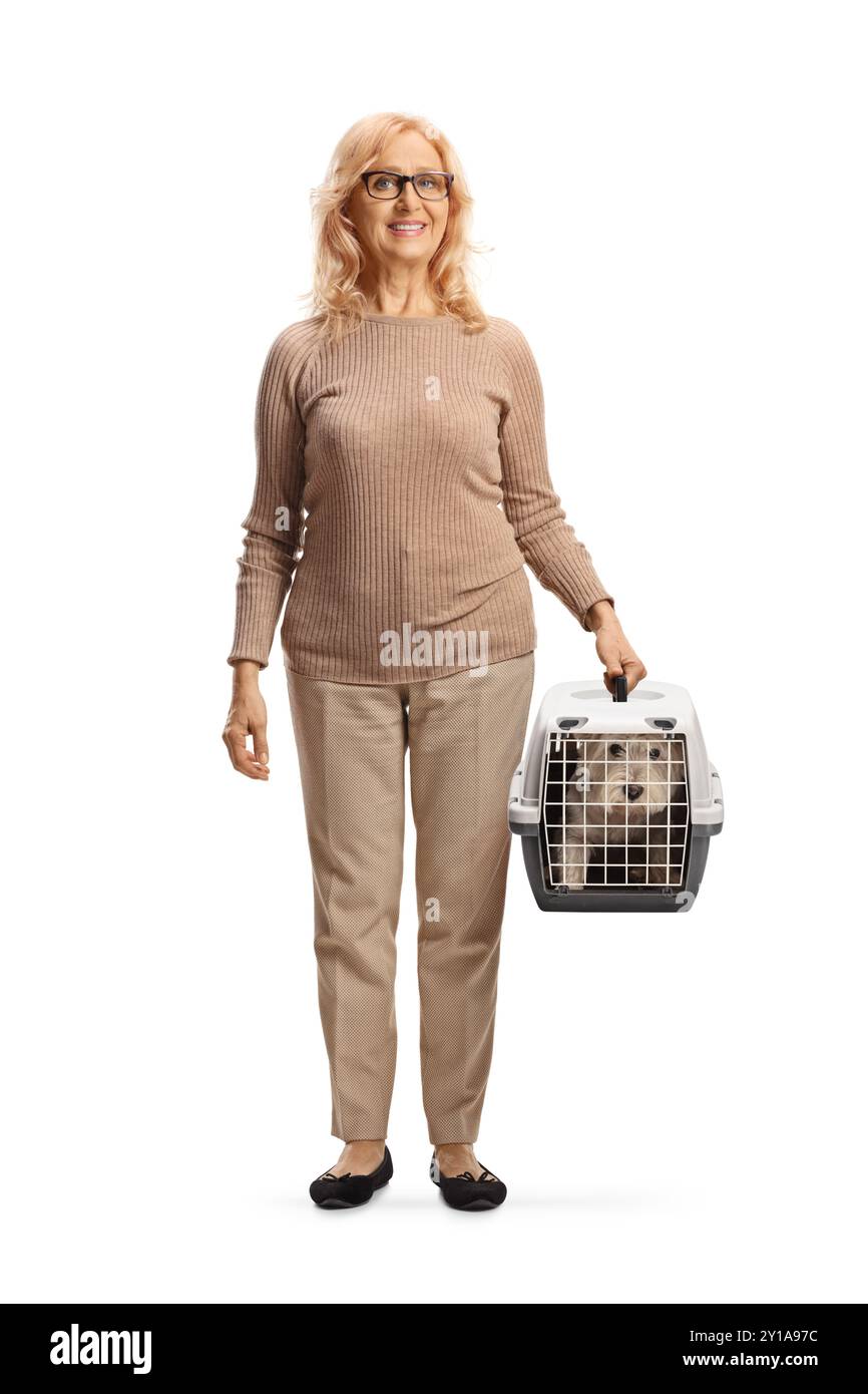 Donna di mezza età che tiene in mano un cane in un trasportino per animali da compagnia isolato su sfondo bianco Foto Stock