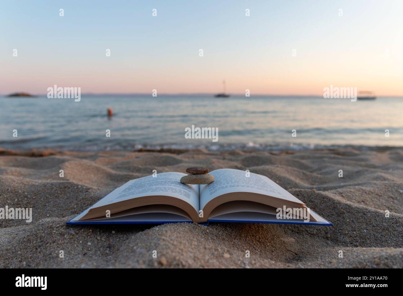 Libri sulla spiaggia accanto al mare al tramonto. Concetto scolastico Foto Stock