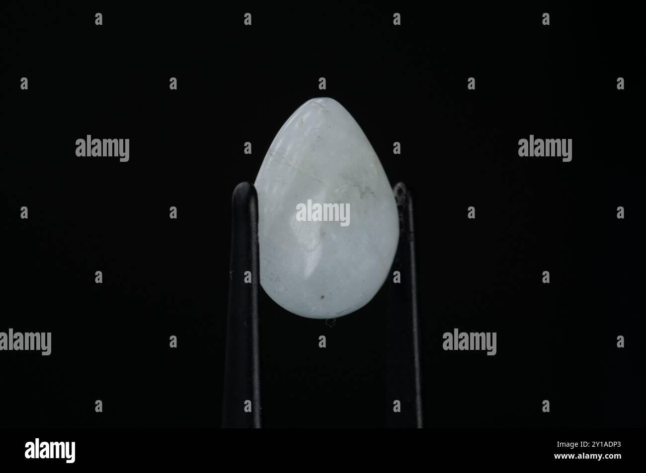 Primo piano di una pietra preziosa bianca a goccia su sfondo scuro. Foto Stock