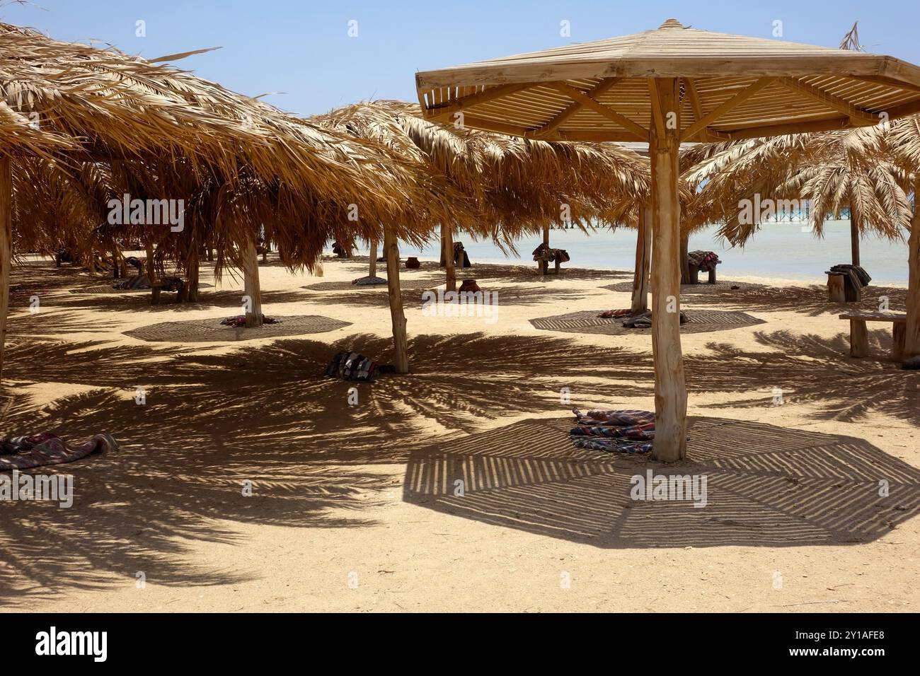 Il sole filtra attraverso gli ombrelloni di Paradise Island a Hurghada, invitante relax su una spiaggia sabbiosa. I visitatori apprezzano la calda atmosfera Foto Stock