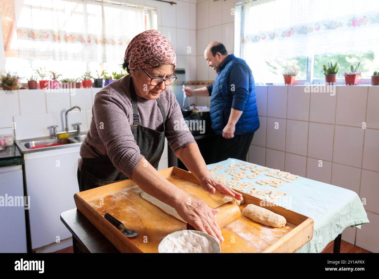 sorridente cucina latina senior e preparare il pasto con suo marito nella loro cucina tradizionale Foto Stock