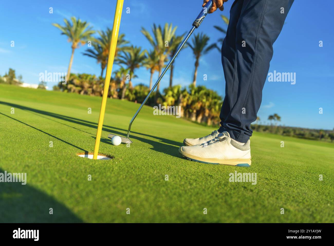 Colpo di raccolto di un golfista maschio che tocca la palla da golf in una buca del campo da golf Foto Stock