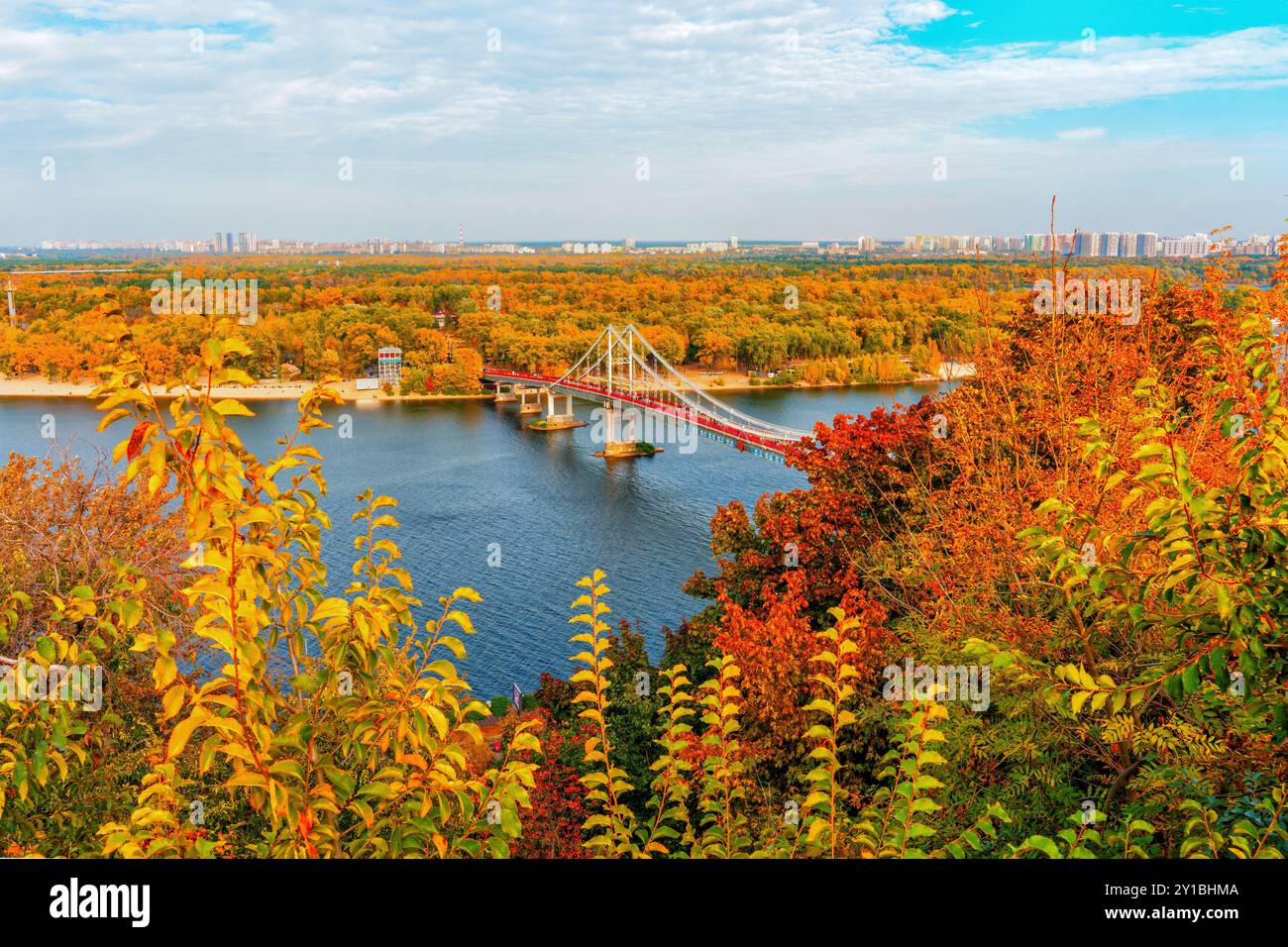 Kiev, Ucraina - 14 ottobre 2023: Vista aerea del ponte pedonale sul fiume Dnieper, che mostra i vivaci colori autunnali e lo skyline della città Foto Stock