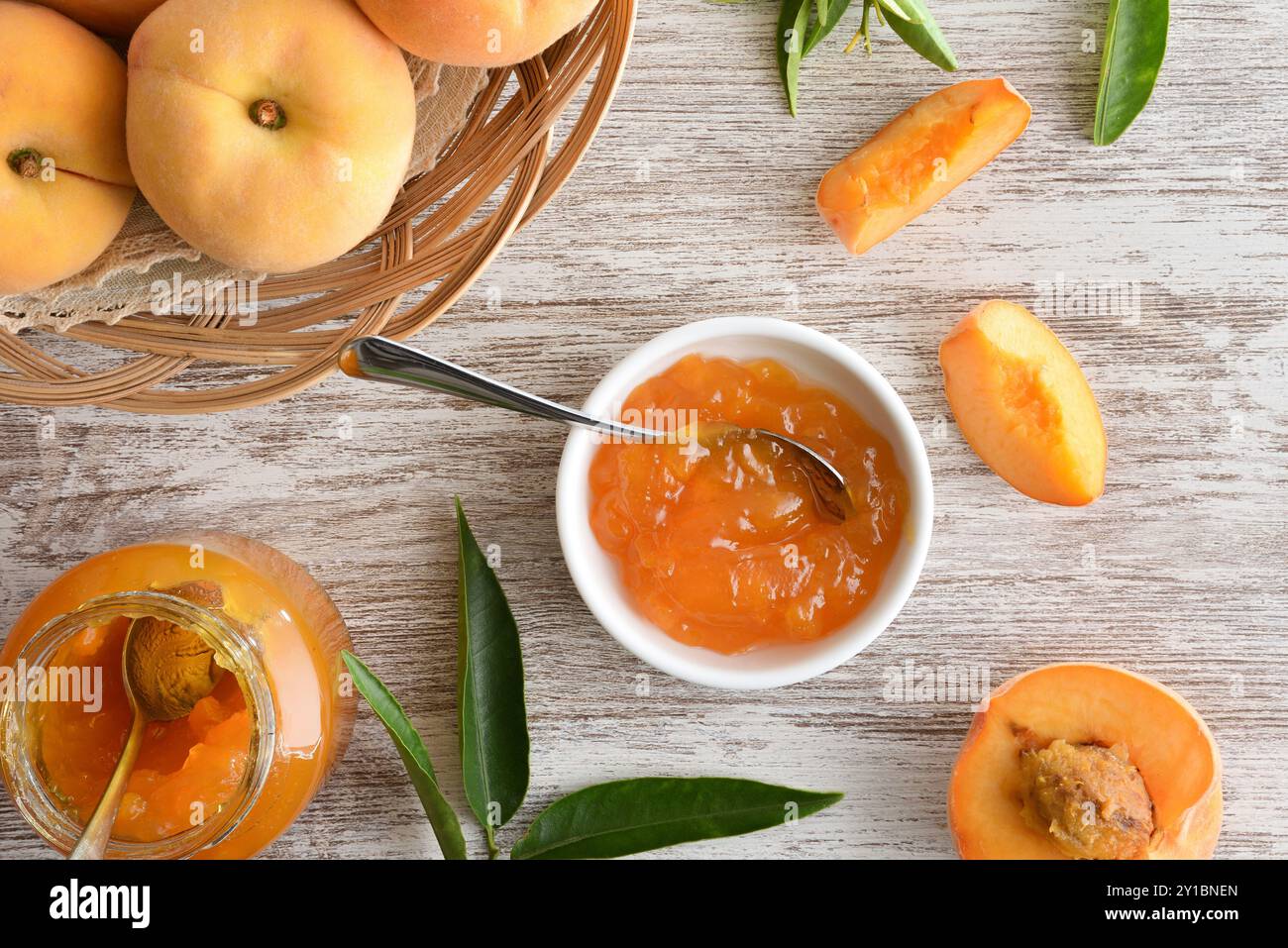 Vasetti con marmellata di pesca su un tavolo di legno e cestino con frutta. Vista dall'alto. Foto Stock