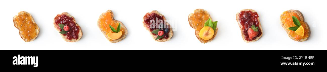 Set di pane tostato con vari marmellati di frutta decorato con pezzi di frutta isolati su sfondo bianco. Vista dall'alto. Foto Stock