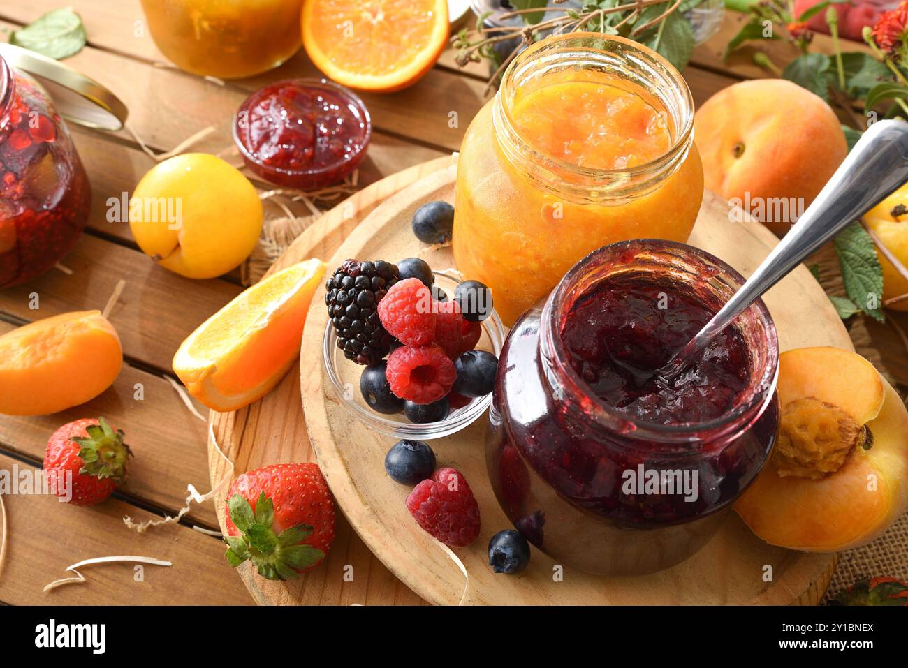 Marmellate naturali fatte in casa di vari tipi di frutta in vasetti su un tavolo di legno in campagna. Vista rialzata. Foto Stock