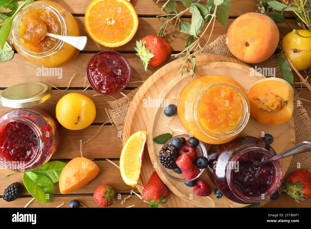 Marmellate naturali fatte in casa di vari tipi di frutta in vasetti su un tavolo di legno in campagna. Vista dall'alto. Foto Stock