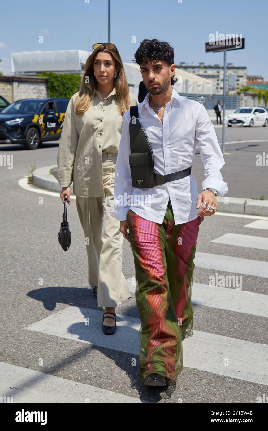 MILANO, ITALIA - 16 GIUGNO 2024: Uomo e donna con camicia bianca e pantaloni rossi e verdi e camicia beige prima della sfilata Prada, Milano Fashion Week Foto Stock