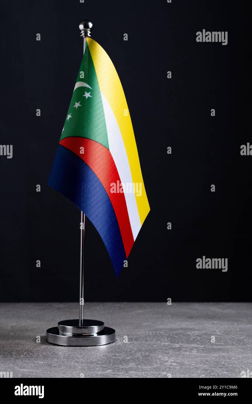 Flagpole in metallo con bandiera delle Comore su tavolo in pietra grigia Foto Stock