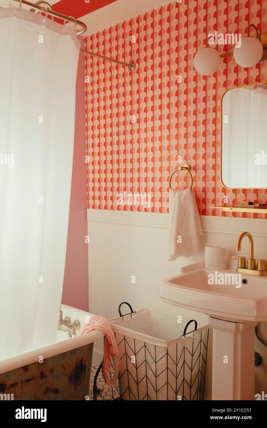 bagno con lavandino a piedistallo, carta da parati a motivi geometrici e vasca a zampa d'artiglio Foto Stock