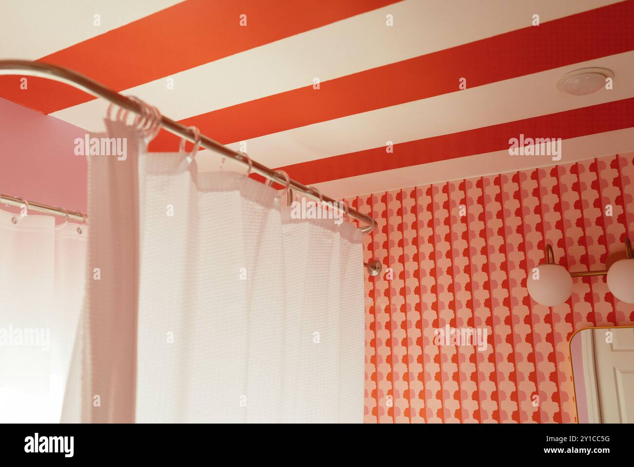 Bagno con soffitto a righe rosse e bianche e carta da parati a motivi geometrici Foto Stock