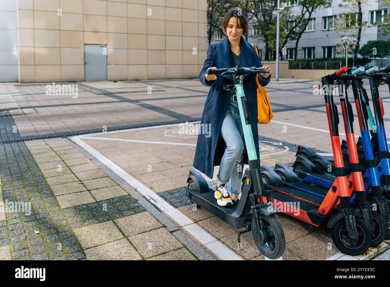 Giovane donna sicura di sé pronta a guidare uno scooter elettrico in città Foto Stock