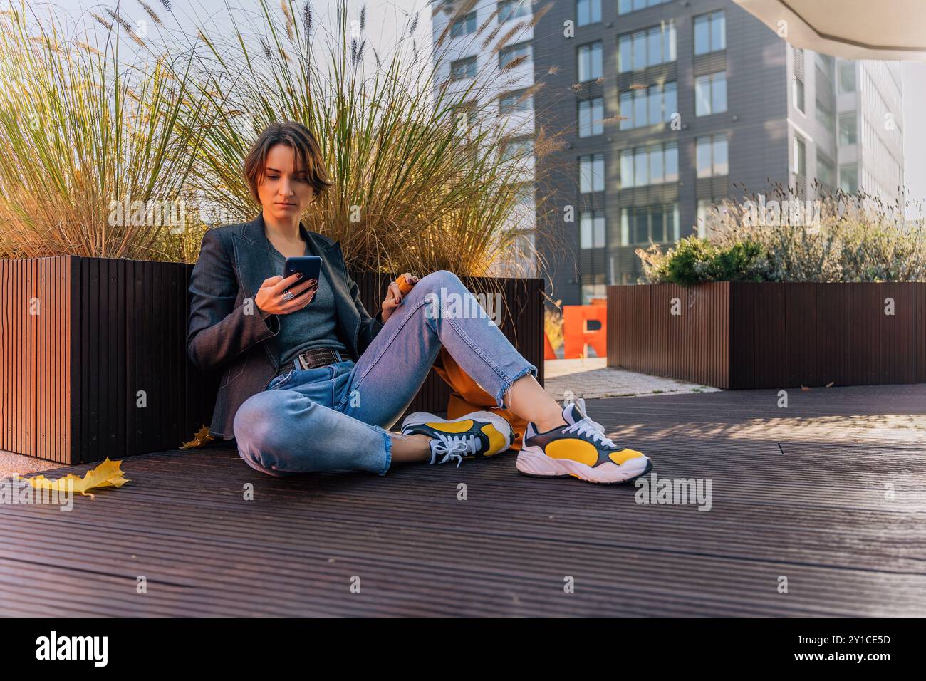 giovane donna rilassata che utilizza lo smartphone in un ambiente urbano all'aperto Foto Stock