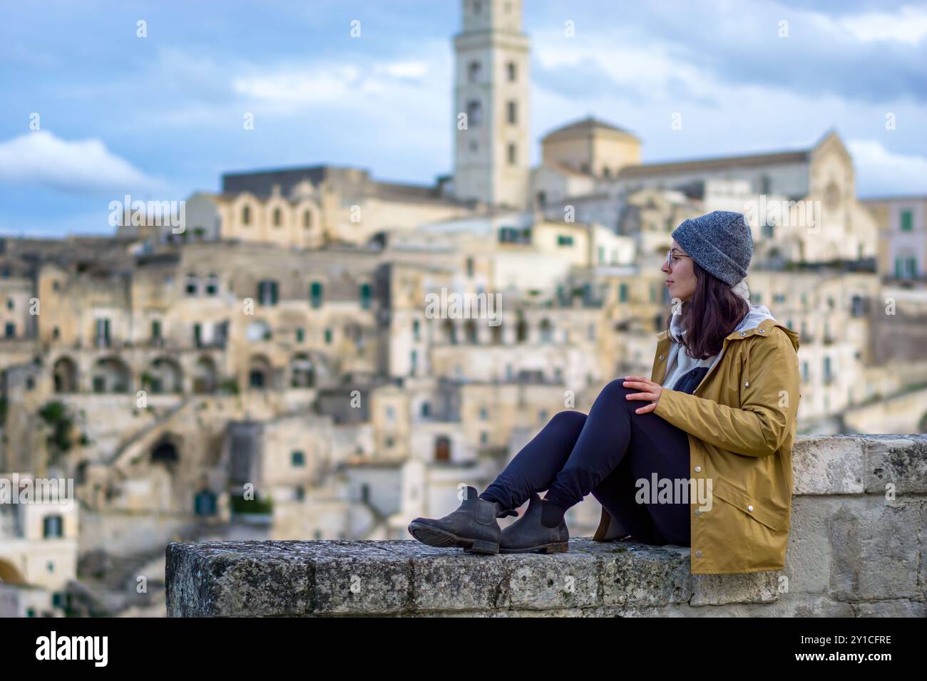 SideView of Woman siede su un muro a Matera, in Italia Foto Stock