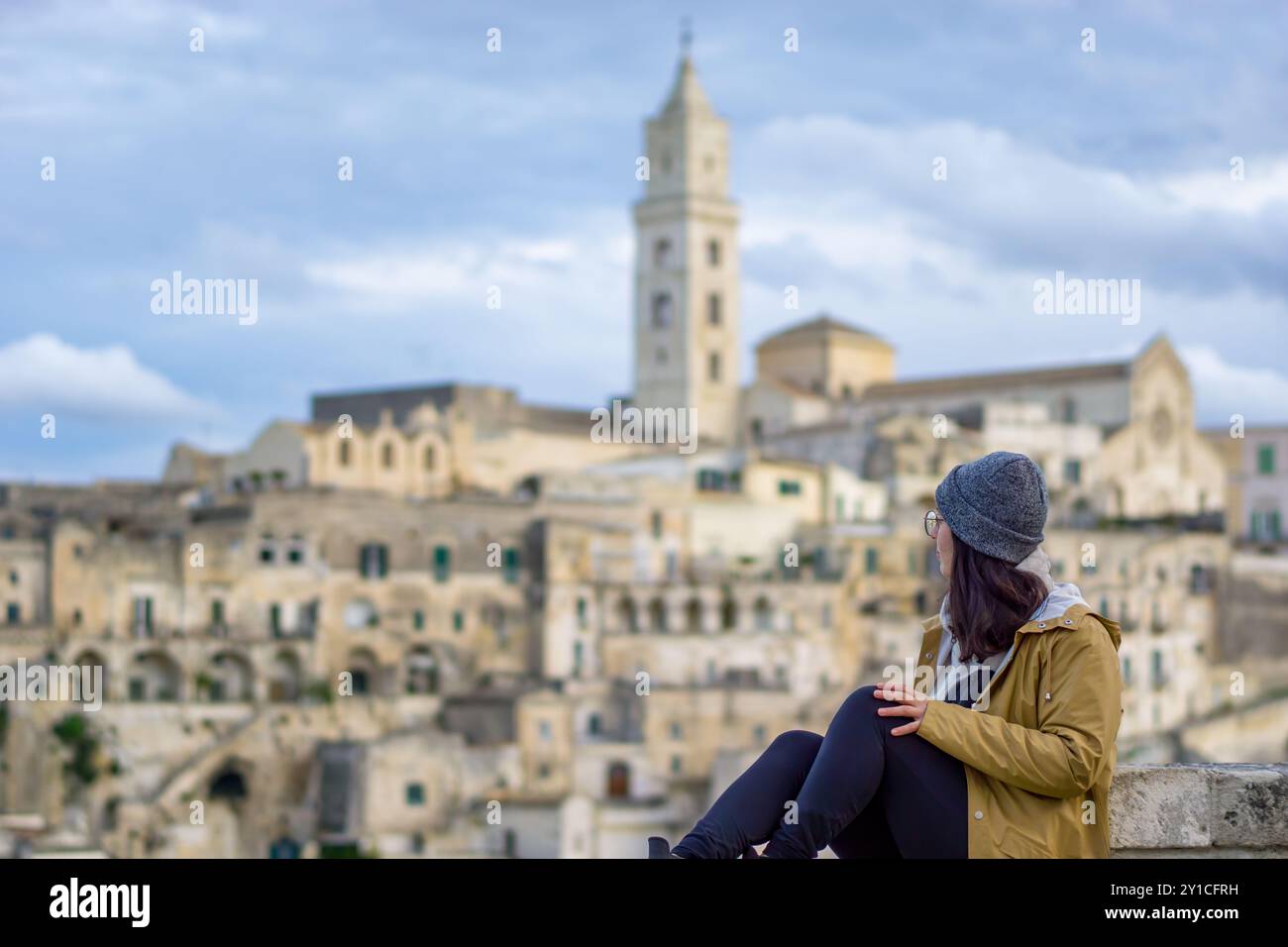 SideView of Woman siede su un muro a Matera, in Italia Foto Stock