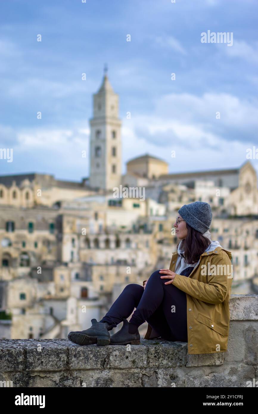 SideView of Woman siede su un muro a Matera, in Italia Foto Stock