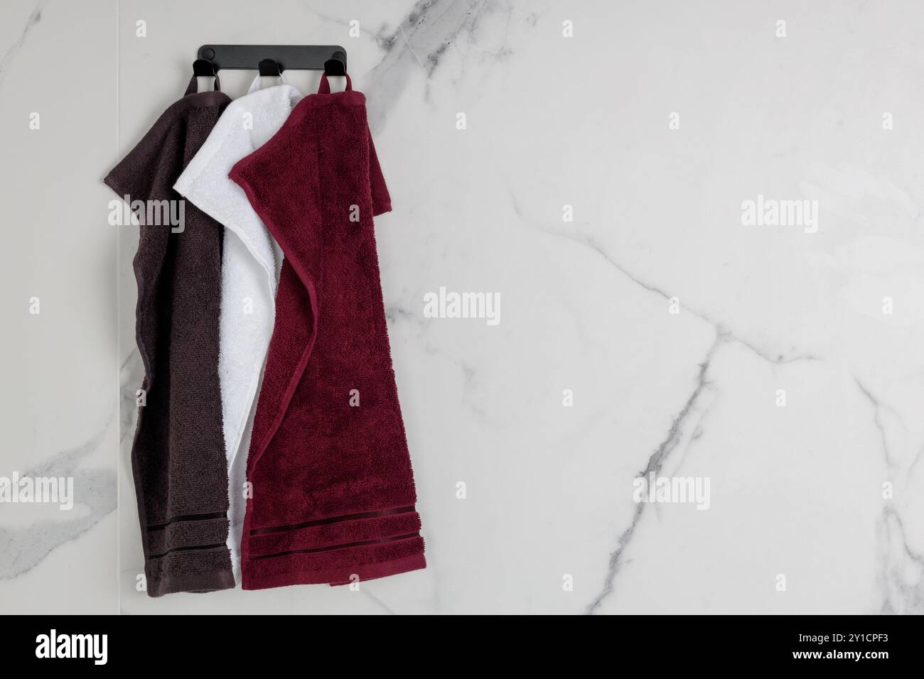 Set di asciugamani sospesi su parete in marmo del bagno Foto Stock