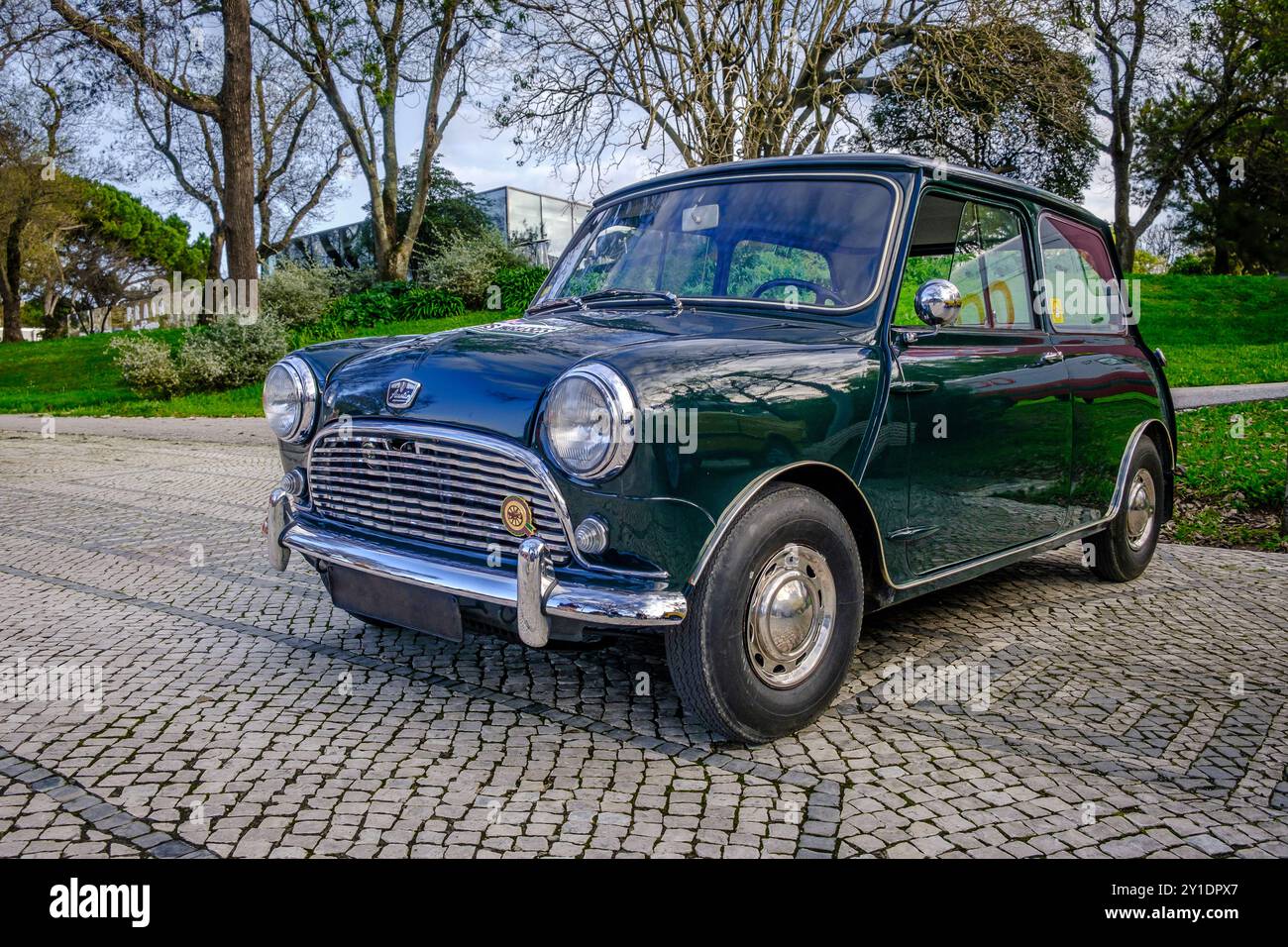 Lisbona, Portogallo - 20 gennaio 2024: Una classica auto verde Mark i Mini o Austin Mini Super-Deluxe con dettagli cromati parcheggiata su una strada acciottolata vicino al parco verde. Foto Stock