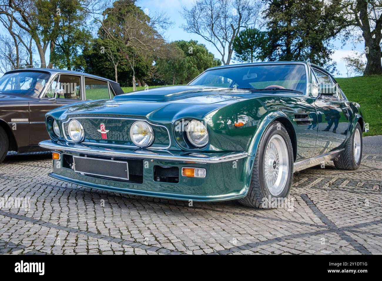 Lisbona, Portogallo - 20 gennaio 2024: Classica Grand tourer Aston Martin V8 Vantage verde scuro parcheggiata su una strada acciottolata, conosciuta come la prima supercar britannica, coupé a 2 porte, con emblema dell'AMOC, celebrazione dell'Aston Martin Owners Club dei 75 anni nel 2010 Foto Stock